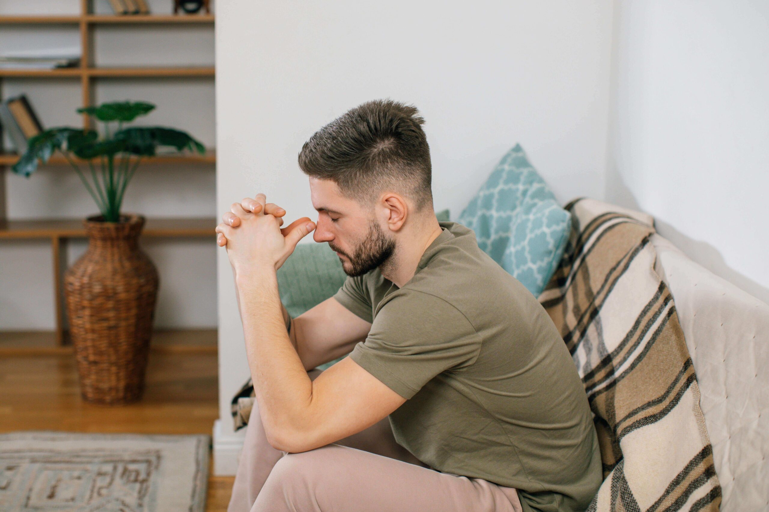 Man sitting on a couch looking stressed, illustrating difficulty with vulnerability addressed in men’s individual relationship counseling in Denver, CO.