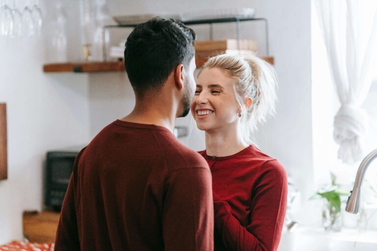 Woman smiling happily while standing close to her partner and looking at him, symbolizing growth and connection through individual relationship therapy for women seeking long term relational healing in Denver, CO.
