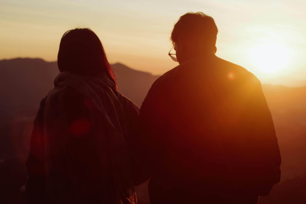 Two people standing side by side watching the sunset, symbolizing connection, reflection, and individual relationship counseling in Denver, CO.