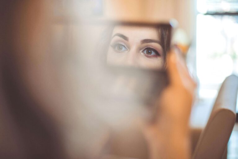 Woman’s eyes visible in a small mirror reflection, representing self-perception explored in self-esteem counseling in Denver, CO.