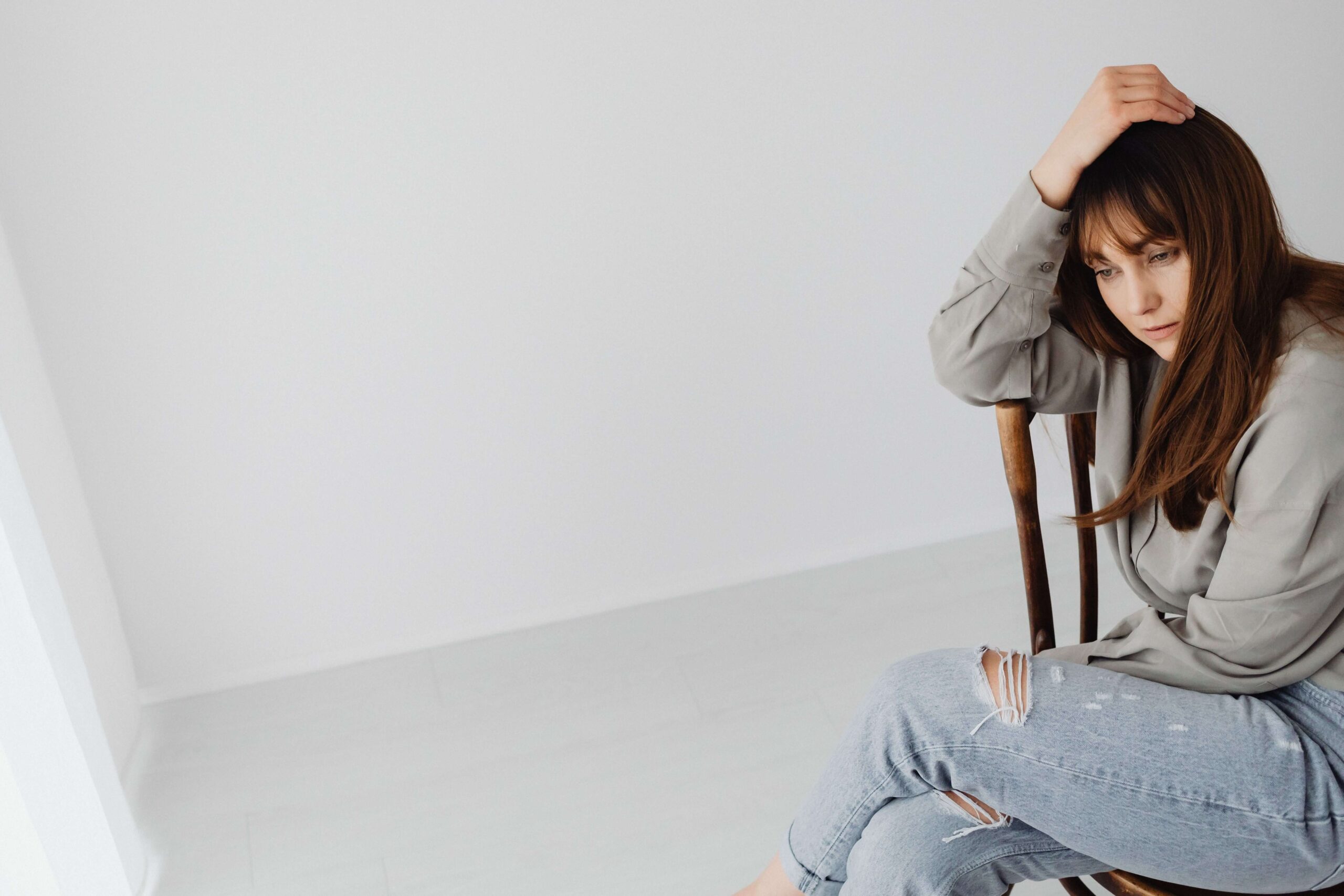 Woman sitting in a chair with a reflective expression, illustrating inner processing and emotional awareness supported through individual relationship counseling for emotional security in Denver, CO.