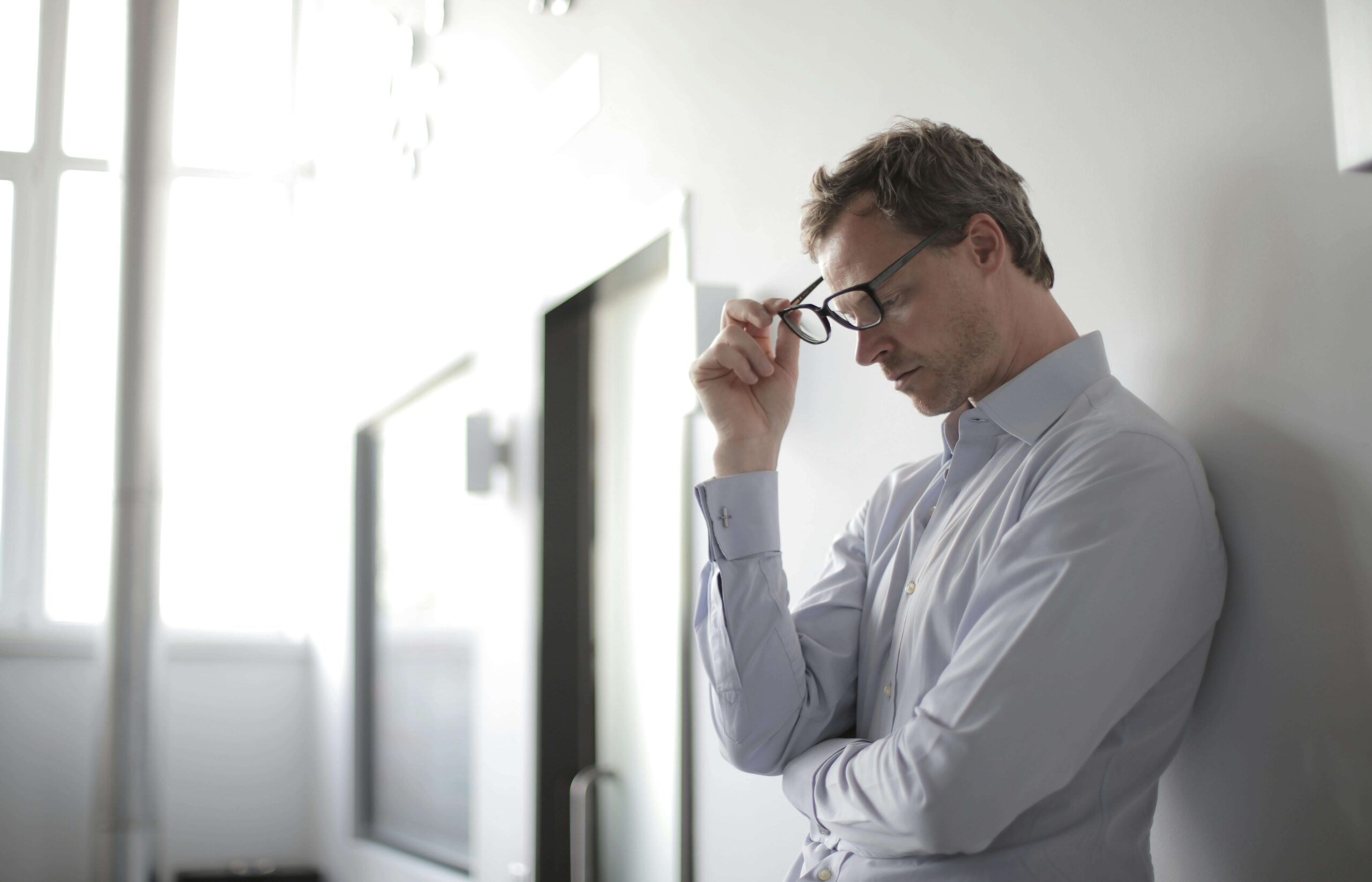 Man taking off his glasses with eyes closed, appearing stressed, illustrating emotional strain that counseling for autistic adults in Denver, CO can address.
