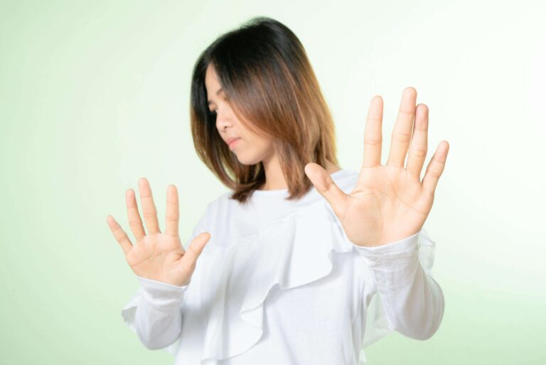Woman holding her hands up in a “no” gesture, representing boundary-setting explored in individual relationship counseling for people pleasing in Denver, CO.