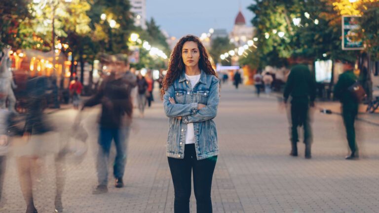 Person standing alone in a crowd, representing emotional isolation and difficulty connecting with others explored through avoidant attachment therapy in Denver, CO.
