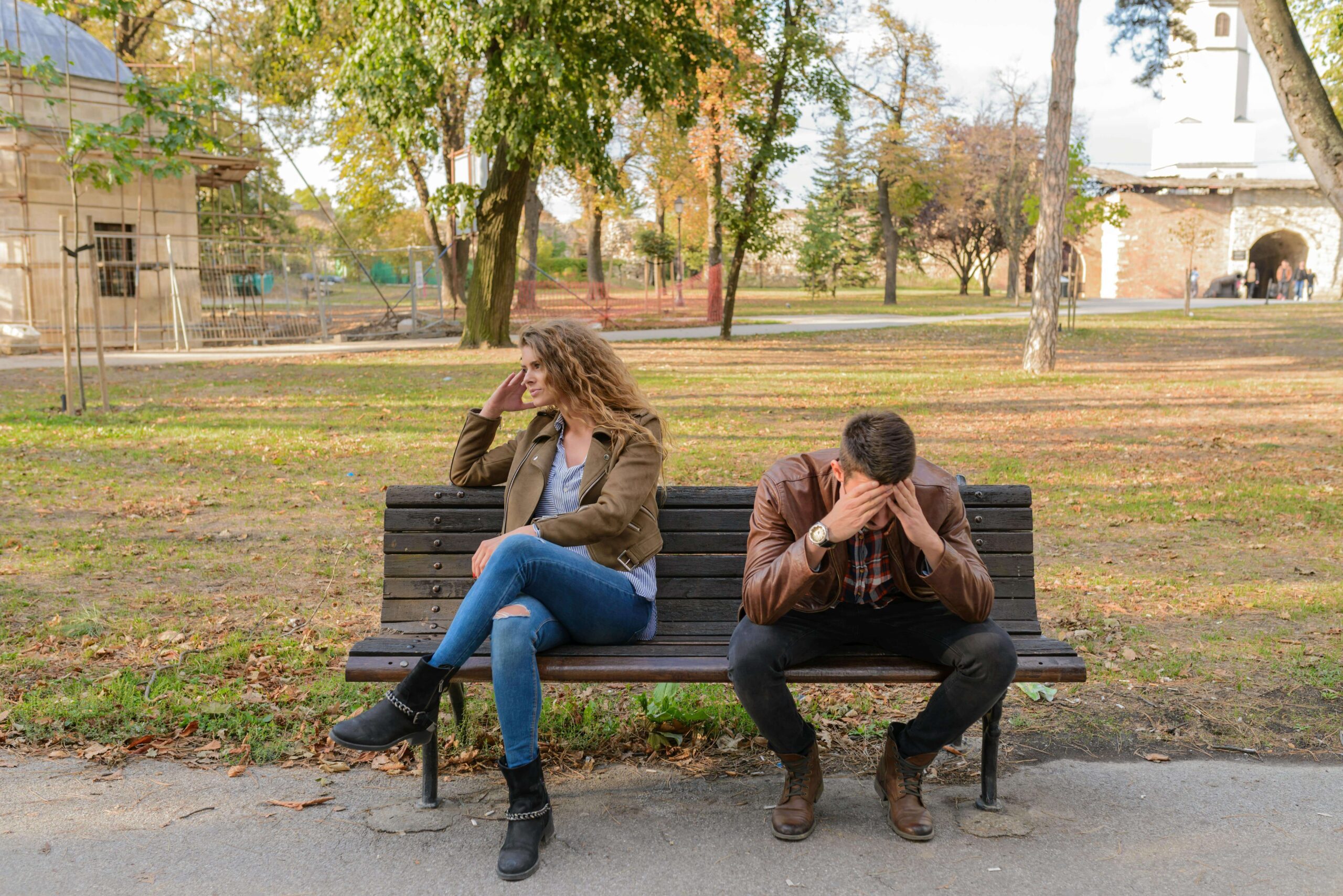 Couple sitting on a park bench turned away from each other, illustrating insecurity and distance addressed in individual relationship therapy for self-confidence in Denver, CO.